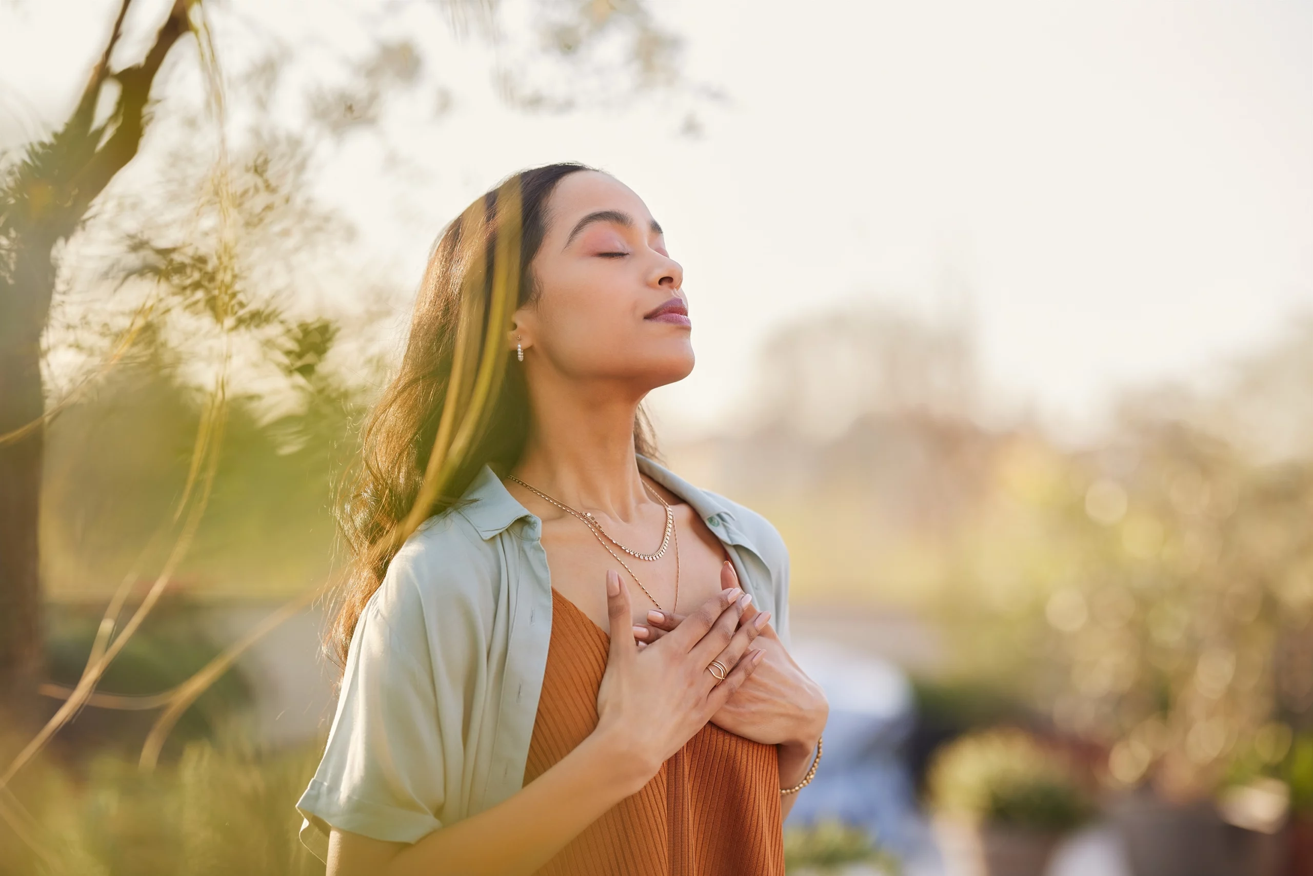 Young woman with her eyes closed and hands against her chest doing breathing exercises